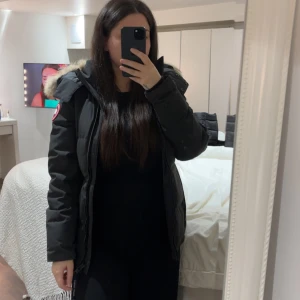 Svart Canada Goose vinterjacka  - Säljer en svart vinterjacka från Canada Goose med klassisk patch på ärmen och stor huva med fluffig päls. Har används endast en vinter säsong 