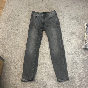Grå slim straight jeans Jack & Jones - Snygga grå jeans från Jack & Jones i modellen Slim Straight Tim. Klassisk femficksdesign, raka ben och normal passform. Jeansen är i denim med en tvättad grå färg som ger en cool vibe. Perfekta för dig som gillar stilrena och enkla jeans. Har använt de ett fåtal gånger.