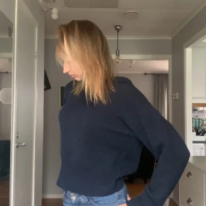 Mörkblå stickad hoodie med huva - Mysig mörkblå stickad hoodie med huva och lång ärm. Tröjan har en relaxed passform och är perfekt för kyligare dagar. Enkel och stilren design som funkar till jeans eller mjukisbyxor.