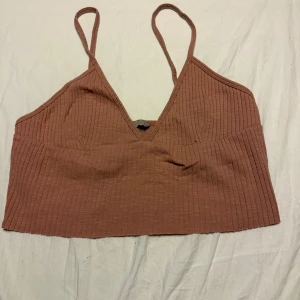 Ribbad rosa croppad linnetopp H&M - Säljer en ribbad croppad linnetopp från H&M i en snygg smutsrosa nyans. Toppen har smala axelband och v-ringning.