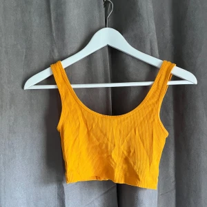 Orange ribbad croppad linnetopp H&M XS - Snygg croppad linnetopp från H&M i en härlig stark orange färg. Toppen är ribbad och har breda axelband samt rundad halsringning. 