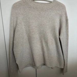 Beige stickad från Mango - En skön stickad tröja i storlek xs och beige. Den har även en liten slott där nere som är en fin detalj. Den är använd men har inte synliga defekter som fläckar osv