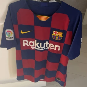 FC Barcelona matchtröja Nike - Säljer en lmtedition FC Barcelona matchtröja från Nike med klassiskt rutigt mönster i mörkblått och rött. Tröjan har korta ärmar, La Liga-patch på ena ärmen och klubbens emblem på bröstet. Materialet är lätt och andas, perfekt för fotboll eller häng med polarna.