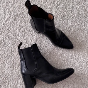 Novita Svarta boots -  svarta stövletter från Novita i skinn med spetsig tå och blockklack. Klassisk design med elastiska paneler på sidorna och dragflik bak. Perfekta för dig som vill ha en stilren och tidlös look. Köpta för 2400kr. 