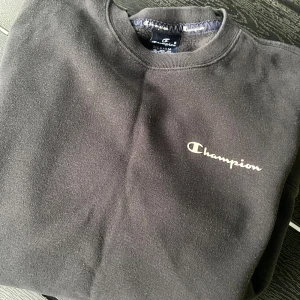 Collegetröja Champion M - Klassisk champion collegetröja med Champion-logga på bröstet och liten logga vid ärmslutet. 