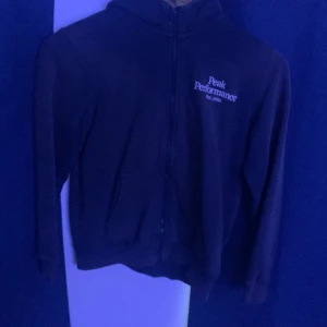 Svart hoodiejacka Peak Performance - Svart hoodiejacka från Peak Performance med dragkedja framtill och broderad logga på bröstet. Jackan har huva, två fickor och är långärmad. Perfekt för dig som gillar en sportig och enkel stil.