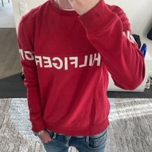Röd Tommy Hilfiger sweatshirt - Snygg röd sweatshirt från Tommy Hilfiger. Perfelt nu inför hösten. Modellen är ca 180cm. Hör av dig vid funderingar!