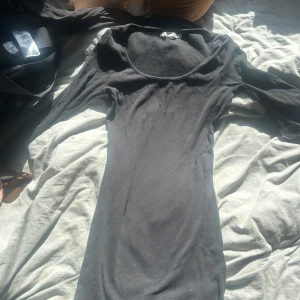 Svart ribbad långärmad klänning - Säljer en svart, ribbad klänning från Lager157 i storlek S med lång ärm och rundad hals. Klänningen är figurnära och har en enkel, stilren design som sitter snyggt på kroppen. Perfekt för dig som gillar minimalistisk stil och vill ha en klänning som är både bekväm och snygg. Används endast 1 gång och finns ej kvar i sortimentet. Pris kan diskuteras men läggs just nu uts för 150kr. Katt finns i hemmet!! 