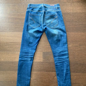 Dondup George  - Snygga blå skinny jeans från dondup med klassisk femficksdesign och kontrastsömmar. Jeansen har en smal passform och är tillverkade i stretchigt denim för extra komfort. Perfekt för dig som gillar en tajt siluett och vill ha en modern look.