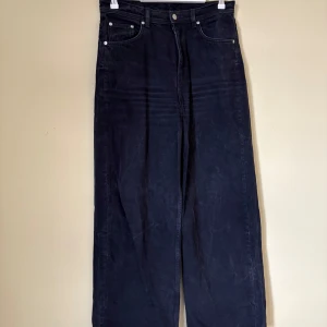 Svarta wide jeans från ARKET - Säljer ett par svarta jeans från ARKET med breda ben och klassisk femficksdesign. Jeansen har hög midja och raka, loose-fit ben för en chill och modern look. Materialet är robust denim och färgen är mörkt svart. Perfekt för dig som gillar avslappnad stil.