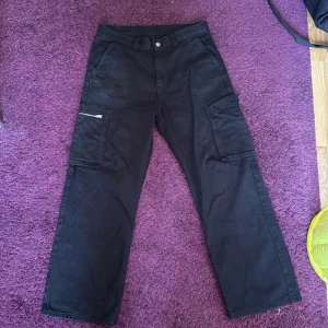 Svarta cargopants från Dr Denim - Svarta cargopants från Dr Denim med breda ben. Byxorna har stora fickor på sidorna, varav en med dragkedja, skön stil och bra loose passform