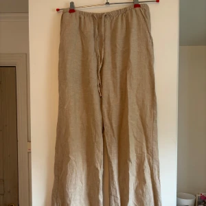 Beige linnebyxor från Gina Tricot XS - Säljer ett par beige linnebyxor från Gina Tricot i storlek XS. Byxorna har en avslappnad passform med breda ben och snörning i midjan. fint skick
