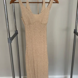 Beige ribbad långklänning H&M XXS - Säljer en beige ribbad långklänning från H&M i storlek XXS. Klänningen har breda axelband och är ärmlös med en snygg, kroppsnära passform. Materialet är stickat och mjukt, perfekt för dig som gillar en enkel men trendig look.
