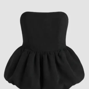 Bandeau topp - Supersnygg svart axelbandslös ballontop  från FB sister  med puffig volangtopp och smockad rygg för extra komfort. Klänningen har en stilren och modern look, perfekt för dig som vill sticka ut med en cool och trendig outfit. Materialet är mjukt och följsamt har inte använt och lappen sitter kvar NY pris 179.