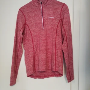 Röd långärmad träningströja Yosemite -  Rosa långärmad träningströja från Yosemite i melerad design. Tröjan har en half zip-dragkedja framtill, hög krage och är tillverkad i mjuk polyester med lite stretch för extra komfort. Stl M