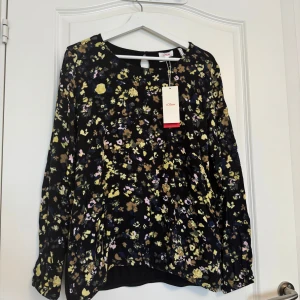 Blommig långärmad blus från s.Oliver - Säljer en svart blus från s.Oliver med blommigt mönster i gult, beige, rosa och blått. Blusen har rund hals, lång ärm och en liten knapp i nacken. Materialet är mjukt och skönt viskos. Perfekt för dig som gillar färg och mönster! Oanvänd. Nypris: 881kr