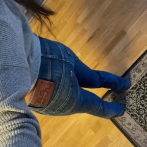 Blå Lee jeans bootcut - Snygga blå jeans från Lee med klassisk brun läderpatch bak. Modellen har bootcut och raka ben, med tydliga sömmar och Lee-logga på bakfickan. Jeansen är tillverkade i slitstarkt denim och har en cool, tidlös look.