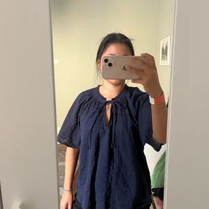 Mörkblå blus med knyt från Esprit - Säljer en mörkblå blus från Esprit i storlek XXL. (Men den passar mig som har storlek S) Blusen har korta, luftiga ärmar och ett snyggt knyt vid halsen. 