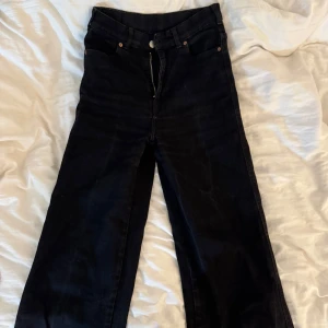 Svarta wider jeans från Dr Denim - Säljer ett par svarta jeans från Dr Denim med breda ben och klassisk femficksdesign. Jeansen har hög midja och raka, loose-fit ben för en chill och trendig look. Materialet är robust denim och färgen är djup svart, perfekt för att matcha med sneakers eller boots.