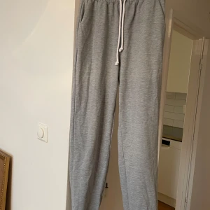 Grå mjukisbyxor med strassdetalj - Snygga grå mjukisbyxor med vit snörning i midjan och elastisk resår. På rumpan finns texten angel i strass. 