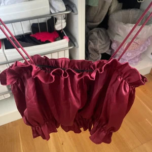 Vinrött linne med volanger - Supersöt vinrött linne med volangdetaljer! Är i storlek Xs men passar S
