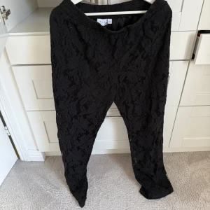 Svarta spetsbyxor från Vila, M - Snygga svarta byxor från Vila i storlek M, täckta med blommig spets som ger en lyxig och cool vibe. 