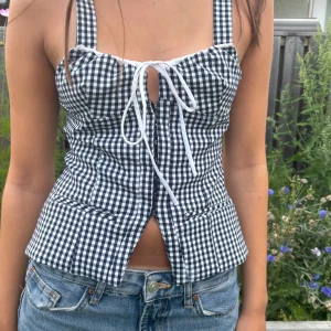 Rutig korsett-topp från Zara XS - Supersnygg svartvit rutig korsett-topp från Zara med breda axelband och knytning framtill. Endast använd ett fåtal gånger, och i toppen skick!!