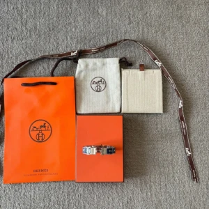 Hermès blå och silver H-armband - Säljer ett ikoniskt Hermès H-armband i silverfärgad metall med blå emaljdetaljer. Armbandet har den klassiska H-loggan framtill och ett stilrent, elegant utseende. Kommer med originalförpackning, dustbag och påse. Perfekt statement piece för dig som gillar lyxiga accessoarer. Kvitton finns!