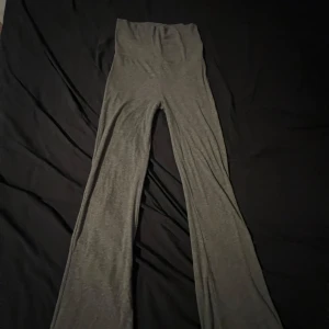 Grå bootcut byxor från Gina Tricot - Säljer ett par grå bootcut byxor från Gina Tricot i mjukt och stretchigt material. De är högmidjade och har en skön passform med vida ben. 