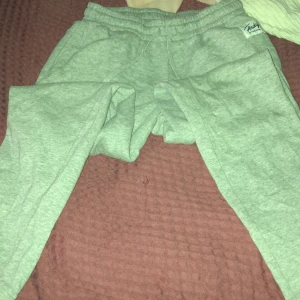 Grå mjukisbyxor Andy by Frank Dandy - Mysiga grå mjukisbyxor från Andy by Frank Dandy i storlek S. De har elastisk midja och är gjorda i mjukt bomullsmaterial med fleece på insidan. Perfekta för chill hemma eller när du vill vara extra bekväm. Snygg enkel design med logga på sidan.