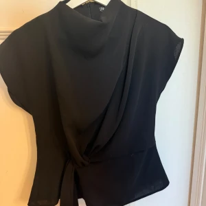 Zara topp - Superfin trendig svart topp från Zara med hög krage och fin knytdetalj! I mycket bra skick och har inga defekter. Kontakta gärna om du har fler frågor!🩷