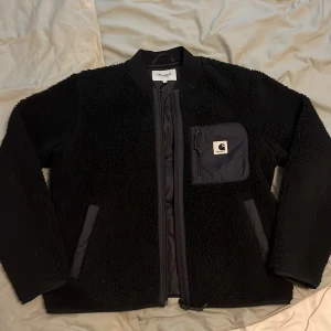Svart Carhartt Fleecejacka - Säljer en svart fleecejacka från Carhartt i storlek M. Materialet är mjuk fleece, det är riktigt bra kvalite på fleecen. Inga defekter. Säljer den för den inte passar mig längre.                               Längd - 59cm, bredd - 54cm.                           Priset kanske kan diskuteras. Skriv vid funderingar. 🌟