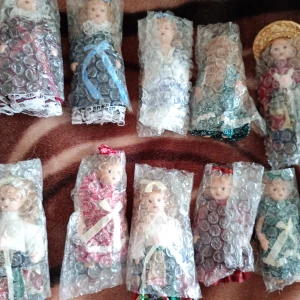 Samlardockor,  17 stycken små dockor med olika kläder och skor,hattar mm. - Bilderna visar en samling dockor inslagna i bubbelplast, klädda i färgglada och detaljerade kläder som påminner om traditionella eller historiska dräkter. 17 stycken små dockor och ligger i en låda ,oanvända. 