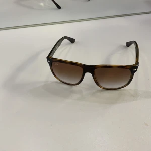 Ray-Ban RB4147 bruna solglasögon - Snygga Ray-Ban RB4147 solglasögon med brunmelerad plastbåge och stora fyrkantiga glas. Glasen är bruna med snygg toning. Perfekt accessoar för att lyfta din stil och skydda ögonen mot solen.