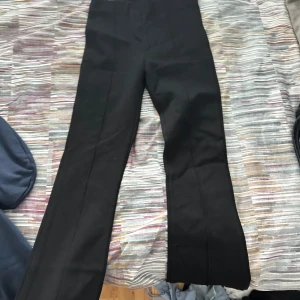 Svarta kostymbyxor med raka ben - Snygga svarta kostymbyxor med klassisk rak passform och pressveck längs benen. Perfekta för en stilren look och passar till skjorta eller t-shirt. Materialet känns mjukt och har en lätt stretch för extra komfort. Från zara 11-12 years men de är väldigt långa i storleken
