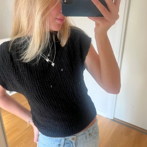 Topp från Zara - Säljer en svart blus från Zara i storlek S. Toppen har en ribbad, krinklad struktur och är ärmlös med rund hals. Jättefin och knappt använd!!💕🙌