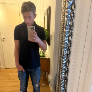 Mörkblå Polo Sport pikétröja S - Tja jag säljer denhär nästan sprillans ny pikétröja från Polo Sport med klassisk krage och två knappar framtill. Den är i S vilket passar dig som är runt 168-173 perfekt för tröjan. Jag säljer den simpelt i behov av pengar. Tröjan har korta ärmar och är gjord i 100% bomull. På bröstet finns den ikoniska röda Polo-loggan broderad. Och som vanligt hesitera inte att skriva om minsta lilla undring om tröjan👏🙌