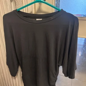 mörkgrå tröja från Stories - En enkel och stilren mörkgrå  tröja från Stories. Tröjan har en rund halsringning och är gjord i mjukt bomullsmaterial. Passformen är loose och den passar perfekt till jeans eller kjol för en chill look.