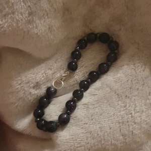 Svart pärlarmband med silverlås - Snyggt armband med svarta, runda pärlor och ett stilrent silverfärgat lås. Pärlorna har en glansig finish och är trätt på en stark tråd. Perfekt accessoar för att ge din outfit lite extra edge.