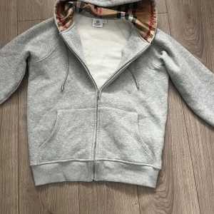 Grå hoodie med rutigt mönster  - Tröjan är knappt använd så den har ett mycket bra skick. Priset går att förhandla. OBS! Endast tröjan ingår dvs inga påsar eller kvitton 