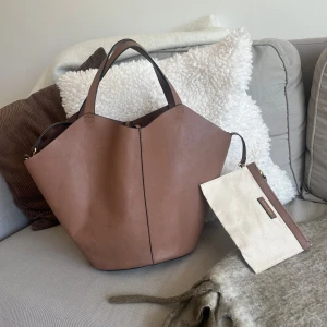 Brun väska från & Other Stories - Superfin brun väska från & Other Stories. Har ett långt axelband och en liten miniväska, samt så kan den knytas 🤎OBS! Den har några små fläckar, men inget jag har tänkt på när jag använt den. Skriv för bilder! 