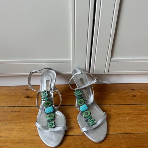 Silvriga sandaler/klacksor med gröna stenar - Snygga silvriga sandaler från pura lópez med smala remmar och klack! Klacken är runt 7 cm. Så den är hög men inte superhög💚