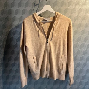 Merinoull zip hoodie - En beige zip hoodie i merinoullblandning.  Från märket alquist clothing. Strolek xxs och passar ca 160 - 170 Pris 300kr. MVH William                                                      3 % Kashmir, 30% merinoull, 50 % nylon, 18 % akryl. 