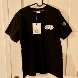 Moncler T-shirt tripple badge - Otroligt fet moncler T-shirt med tripple badge vilket betyder två märken på bröstet och ett vid armen. Självklart Nfc-scan på badgen vid armen. En sällsynt och clean tröja för dig som vill sticka ut ur mängden. Väldigt bra pris och ställ gärna frågor!