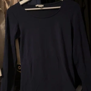 Mörkblå långärmad topp från Amisu - En basic mörkblå långärmad topp från Amisu med rund halsringning. Enkel och stilren modell i mjukt material, perfekt att matcha med jeans eller kjol. Snygg att bära som den är eller under en jacka.