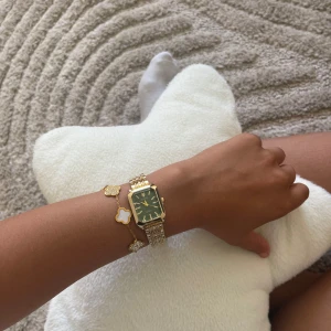 Guldig klocka med grön urtavla justerbar - Snygg klocka  med rektangulärt guldigt armband i metall och en grön urtavla. Klockan har stilrena guldiga visare och index, samt en klassisk länkdesign. Perfekt accessoar för att lyfta din outfit. Bandet legering, ej vattentätt, justerbar