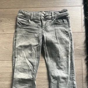 Grå jeans från Gina Tricot, stl 158 - Grå jeans från Gina tricot med en silverfärgad stjärna på en fickan där bak.