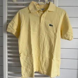 Gul piké t-shirt från Lacoste - Fräsch gul piké från Lacoste med klassisk krage och korta ärmar.