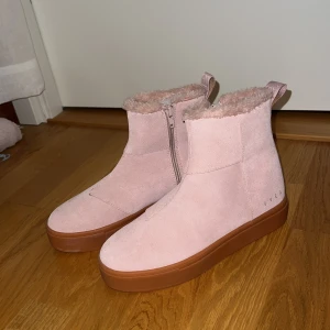 Rosa boots från Svea med fuskpäls - Aldrig använda. Snygga ljusrosa boots från Svea med mjukt fuskpälsfoder och dragkedja på sidan. Ovandel i mocka och brun platt sula ger en cool kontrast. Perfekta för kalla dagar och riktigt sköna att dra på sig snabbt.