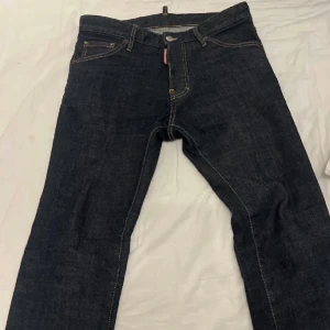 DSQUARED2 Cool Guy Jeans mörkblå - Säljer ett par DSQUARED2 Cool Guy Jeans i mörkblå denim. Klassisk femficksmodell med snygga kontrastsömmar och röd DSQUARED2-tag vid fickan. Italienskt hantverk och riktigt schysst passform för dig som gillar stilrena jeans.